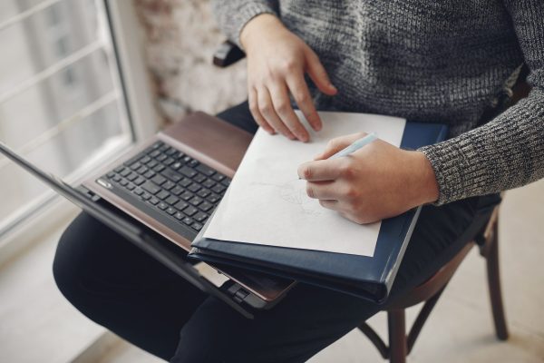 Handsome man in a gray sweater.  Businessman working in a office. Guy with a laptop.